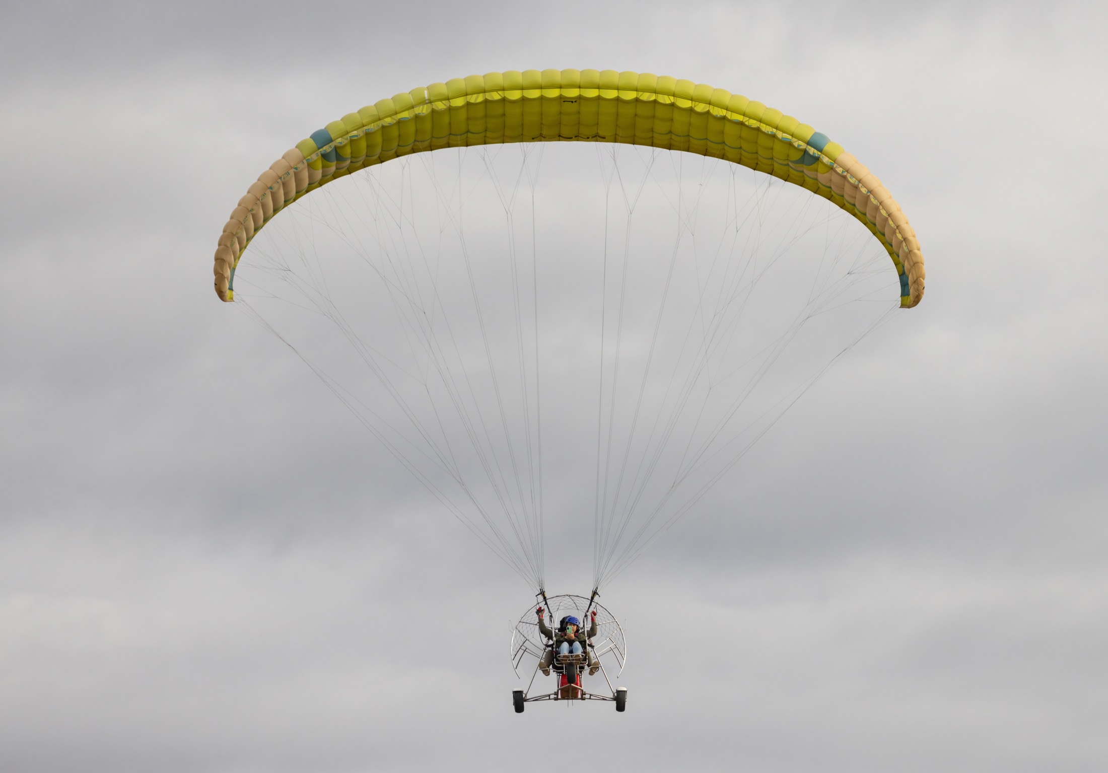 Two people flying in a tandem paramotor above a tropical river landscape